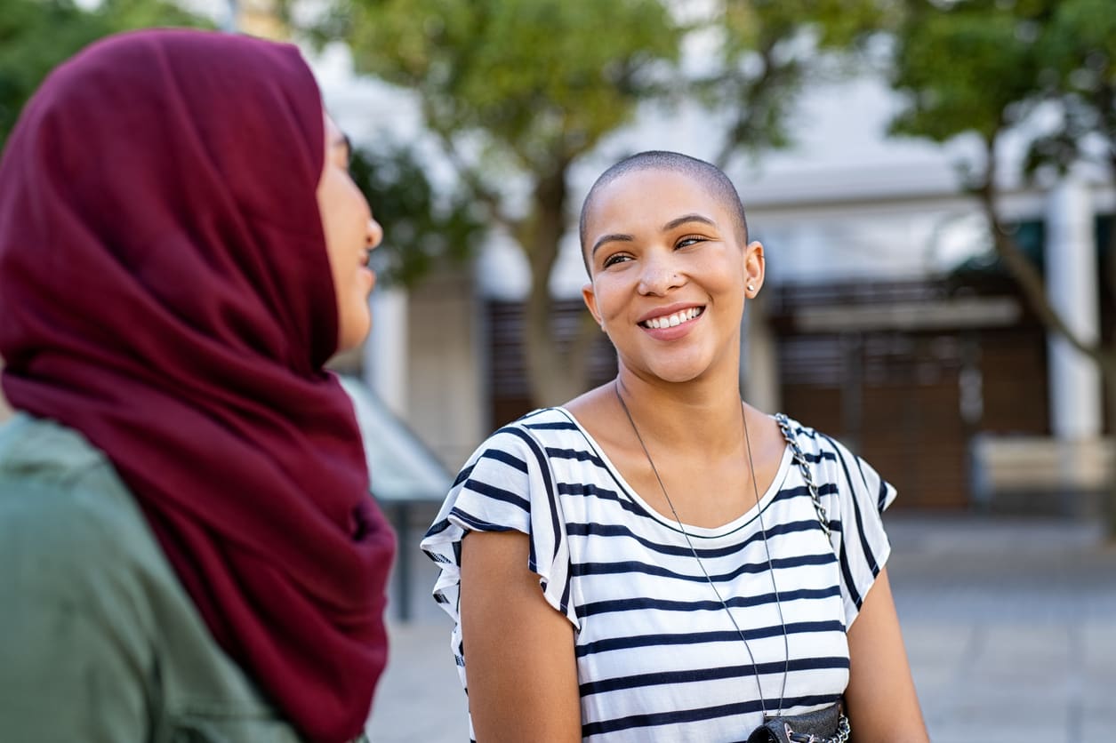 Women talking outside, one wearing a hijab