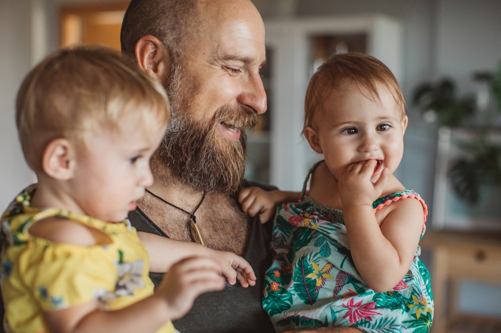 Dad with beard holding twin toddler girls