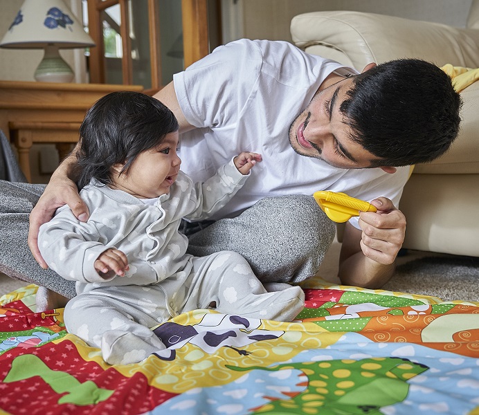 Baby and dad playing with toys on play mat