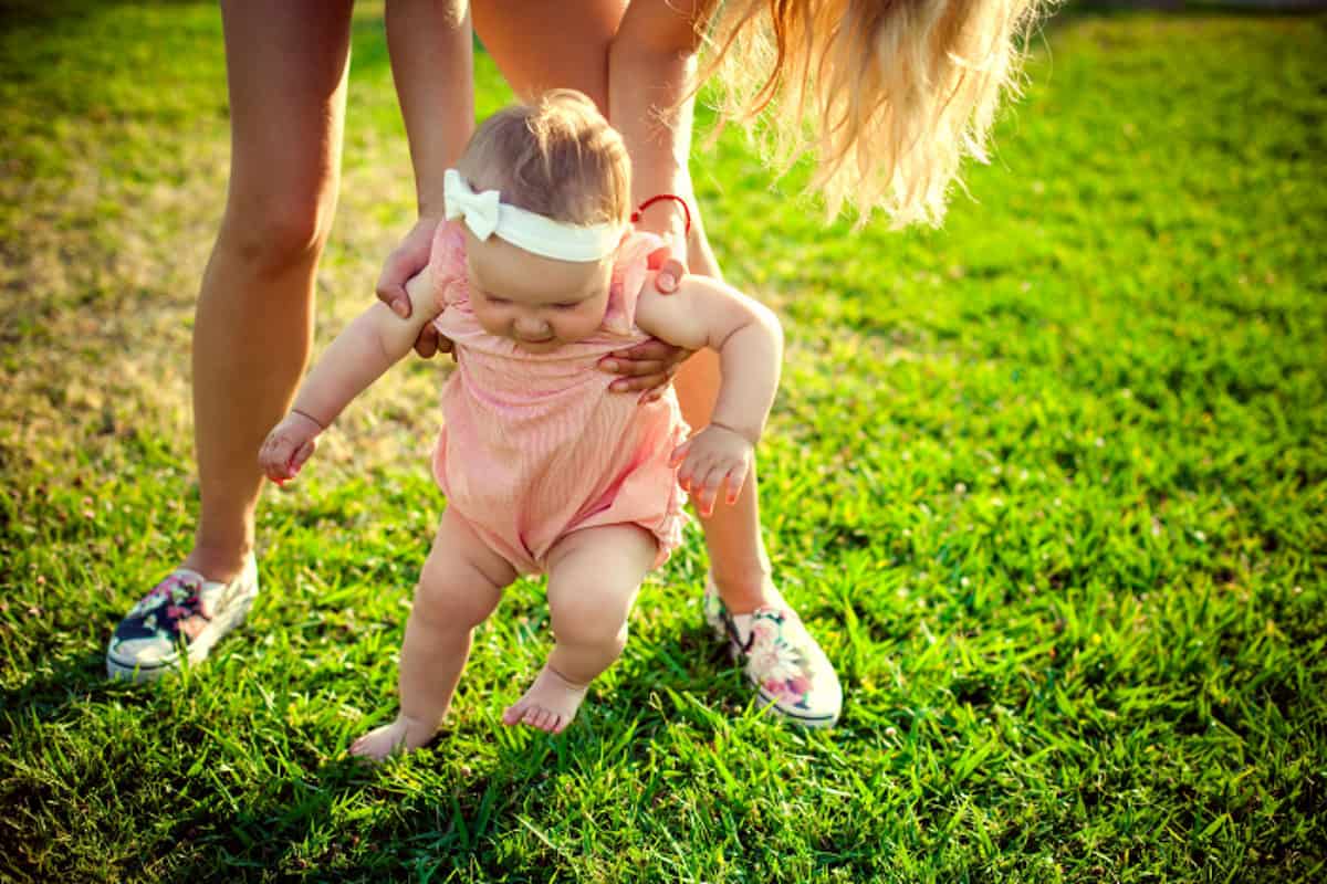 Photo of a baby learning to walk on grass