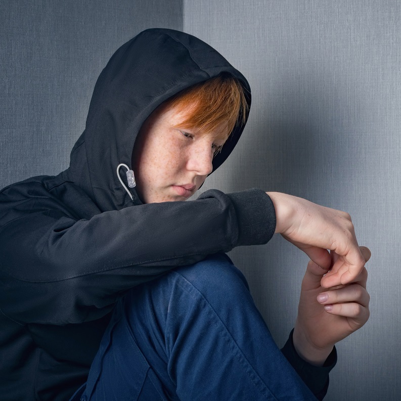 Sad teenage boy wearing a grey hoodie