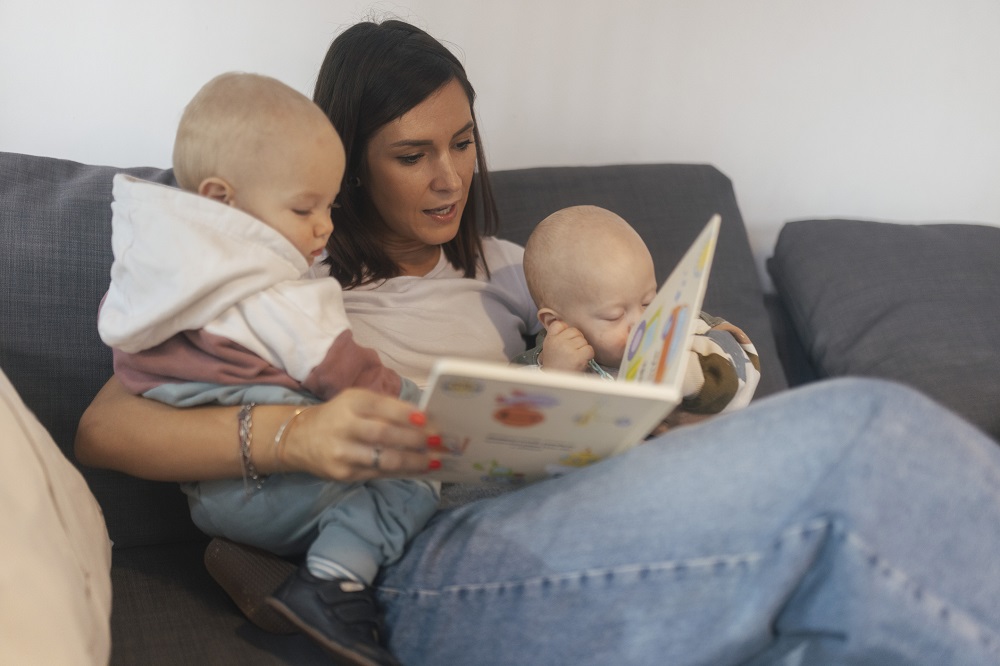 Mum reading a picture book to her twin toddlers