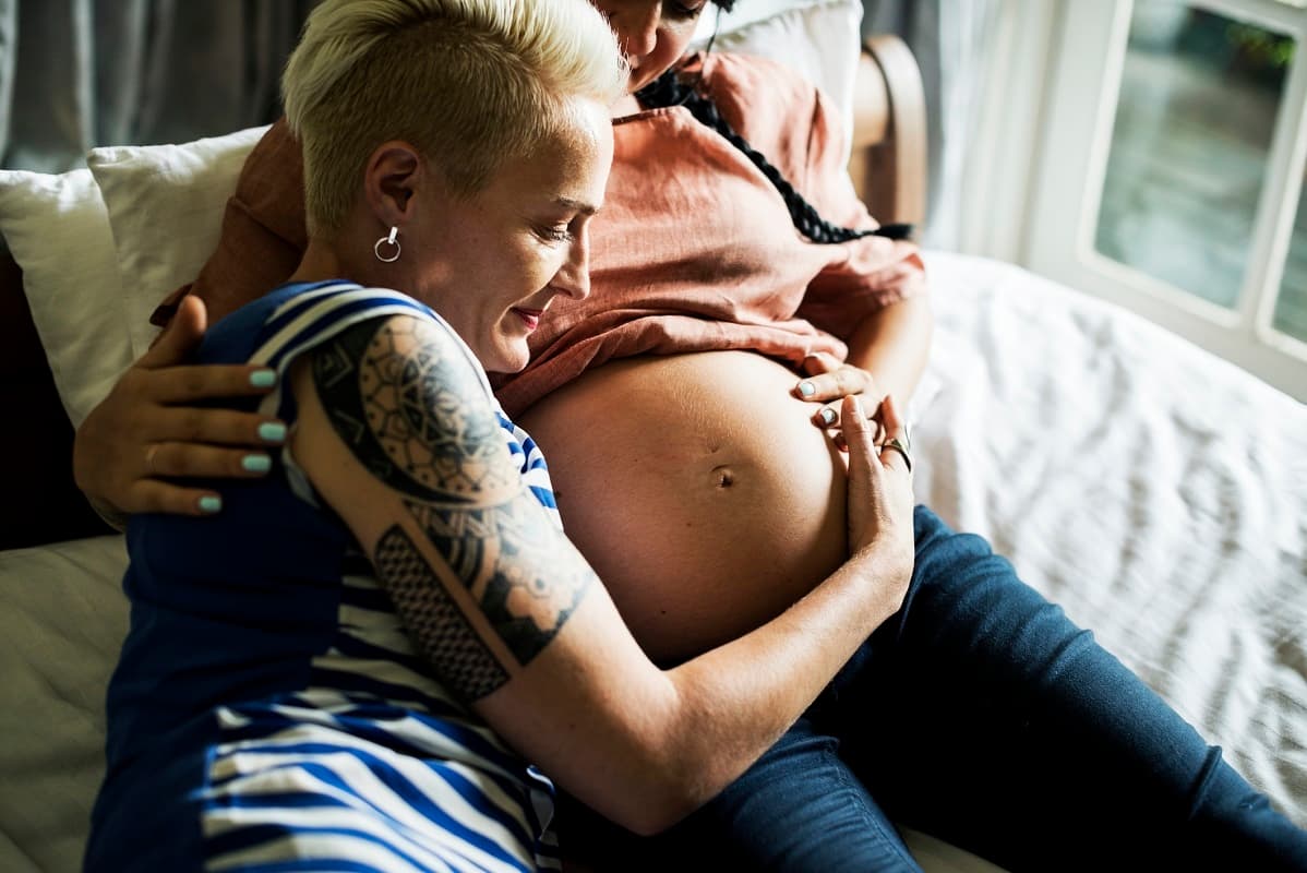 Woman holding the pregnant tummy of her partner