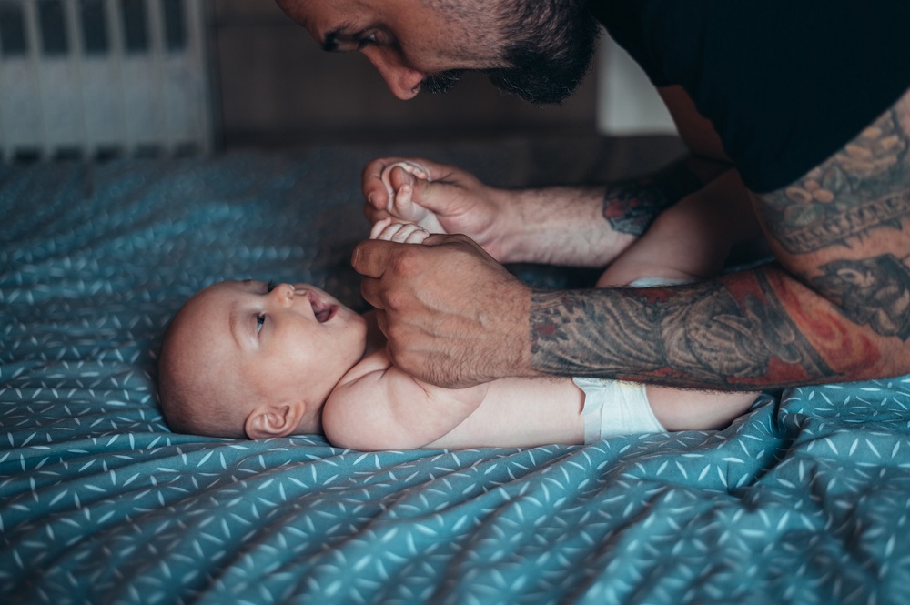 Dad with tattoos smiling at his baby