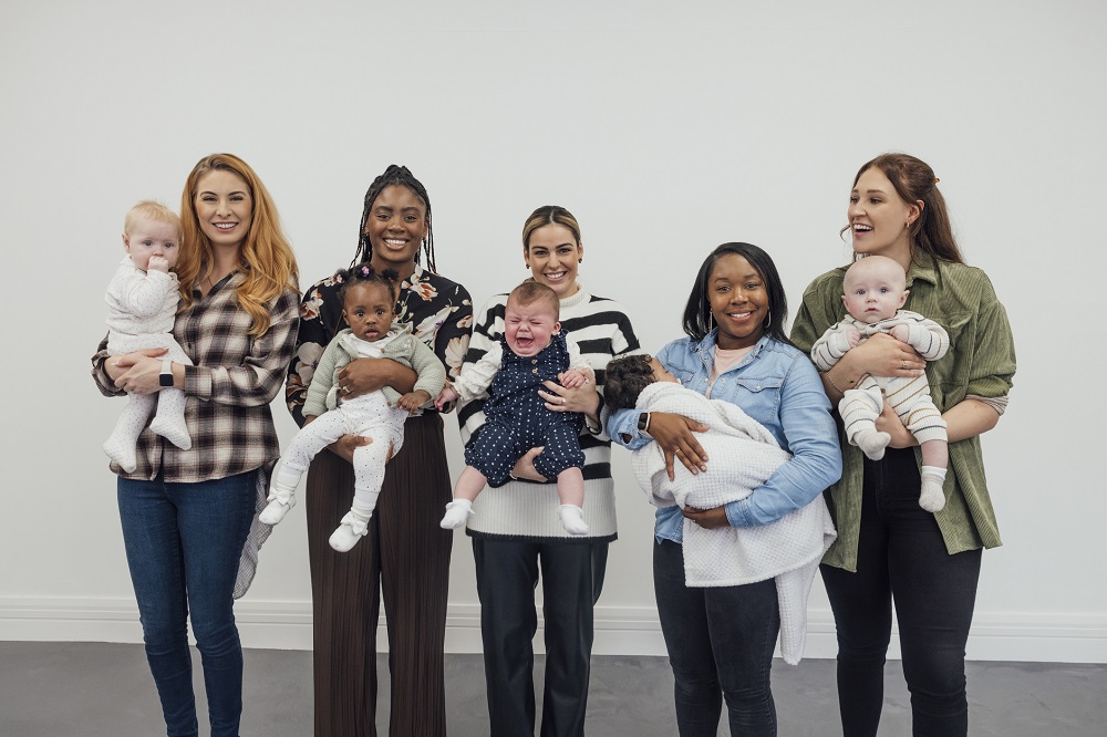 Group of mums holding their babies and smiling