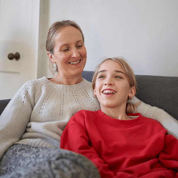 Happy mother and daughter sitting on a sofa