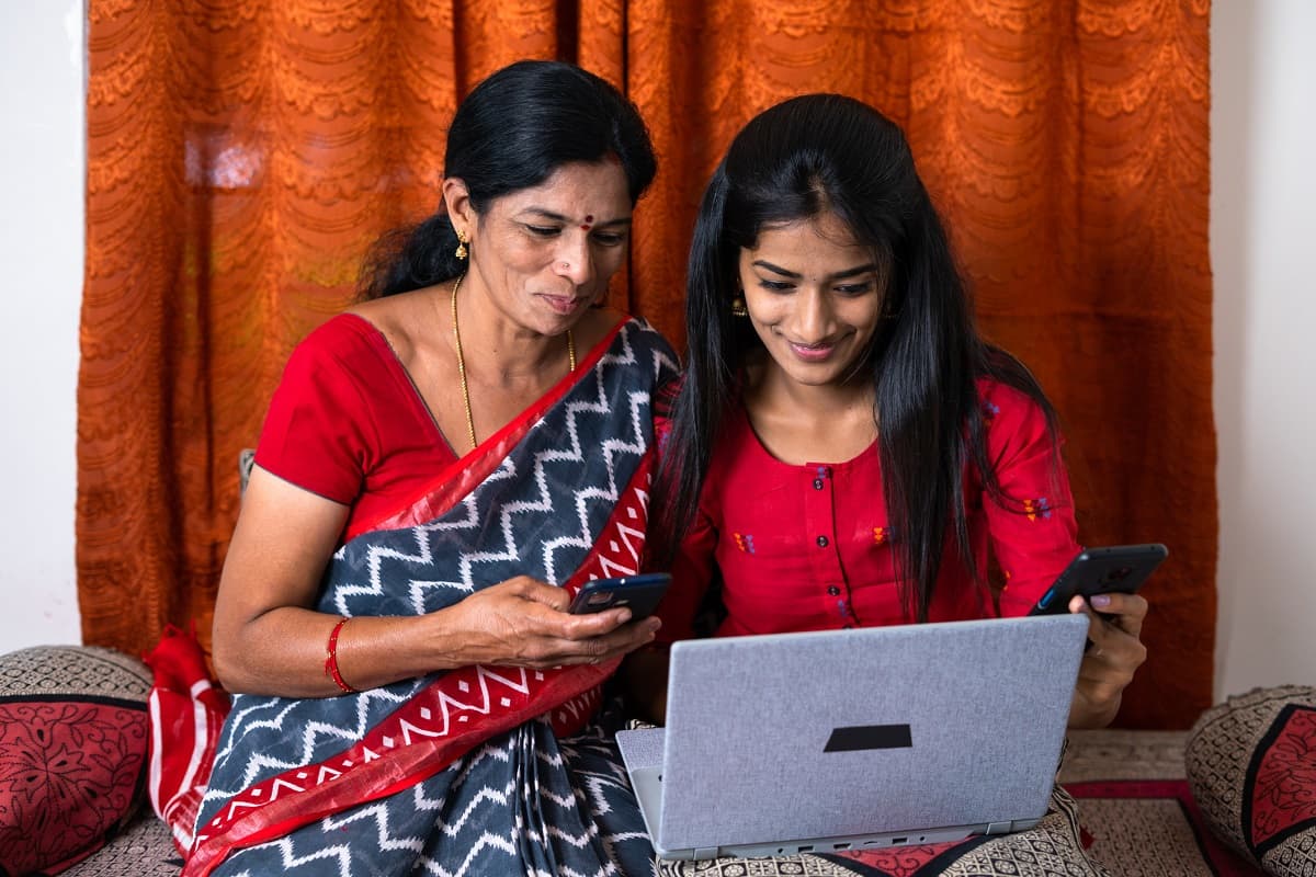Mother wearing a sari looking at a laptop with her teenage daughter