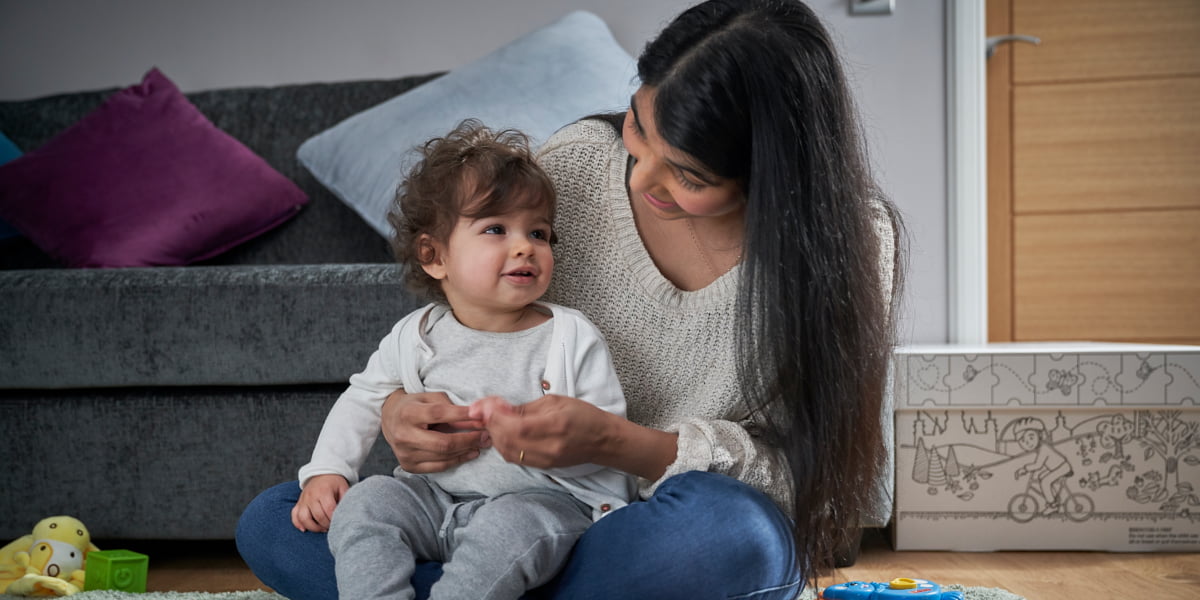 Mum and toddler sitting on the floor, a Baby Box in the background