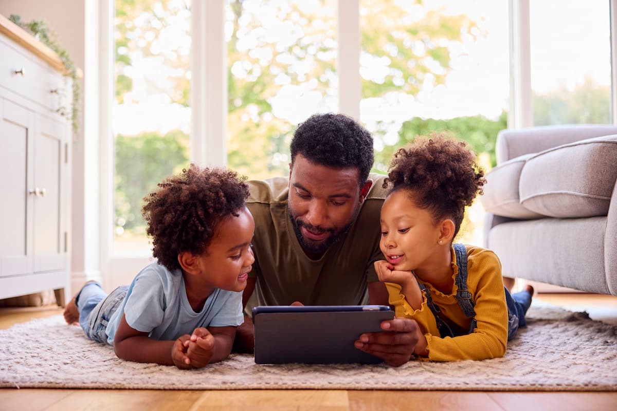 Dad looking at a tablet with his two young children