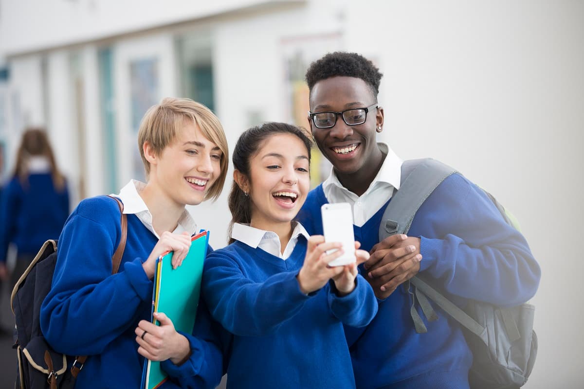 Teens in school uniform looking at a mobile phone