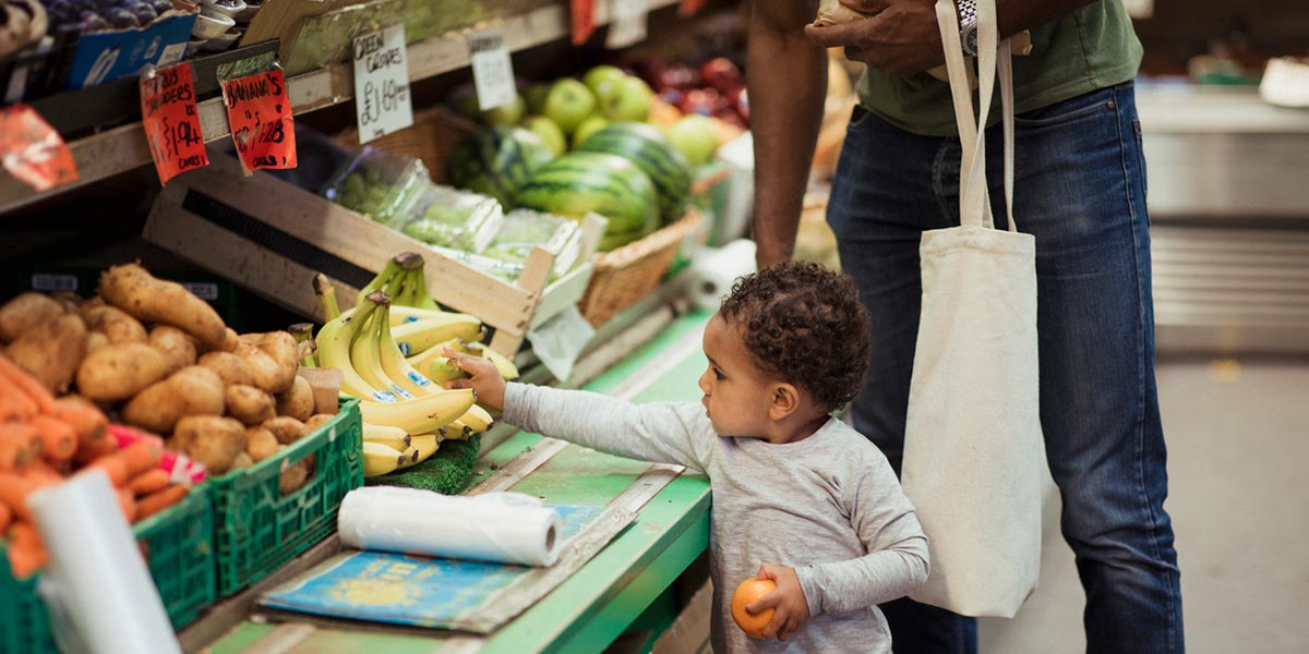 Toddler choosing fruit and veg in the supermarket with dad