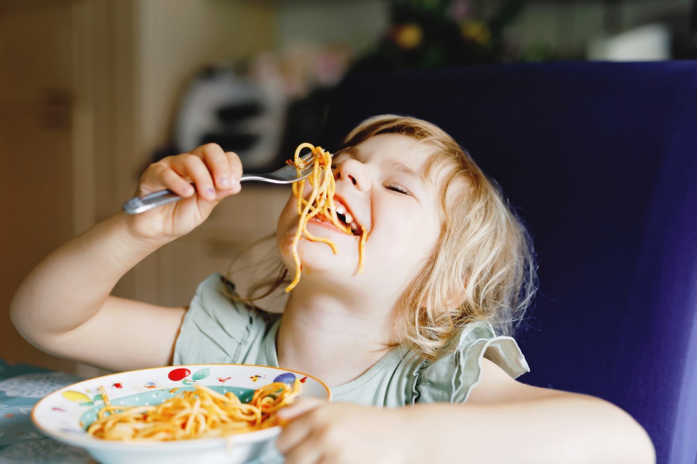 Young child eating spaghetti with a fork