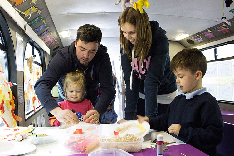 Family with toddler and young boy doing craft activities on the PlayTalkRead bus