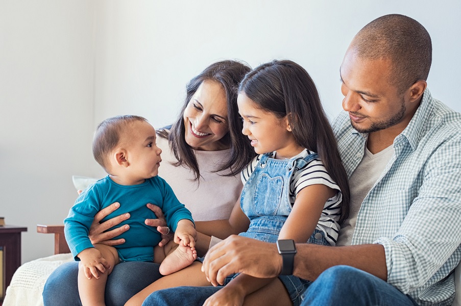 Mum and dad with baby and young girl sitting on a sofa