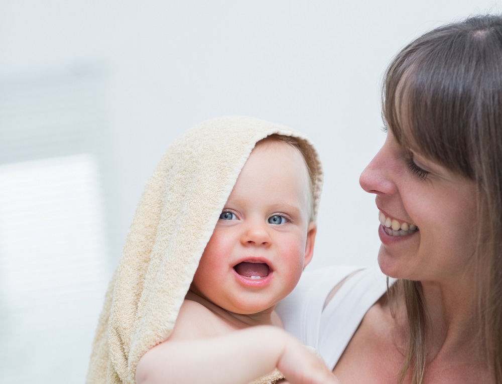 Smiling mum holding her baby wrapped in a towel