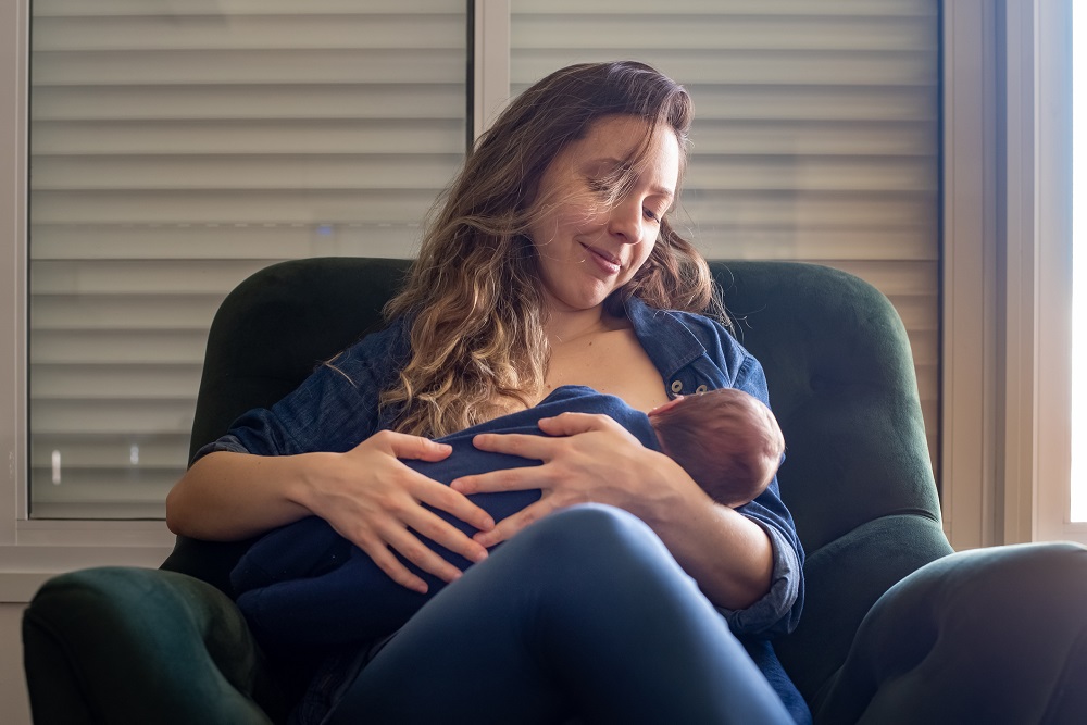 Mother sitting in an armchair breastfeeding her baby