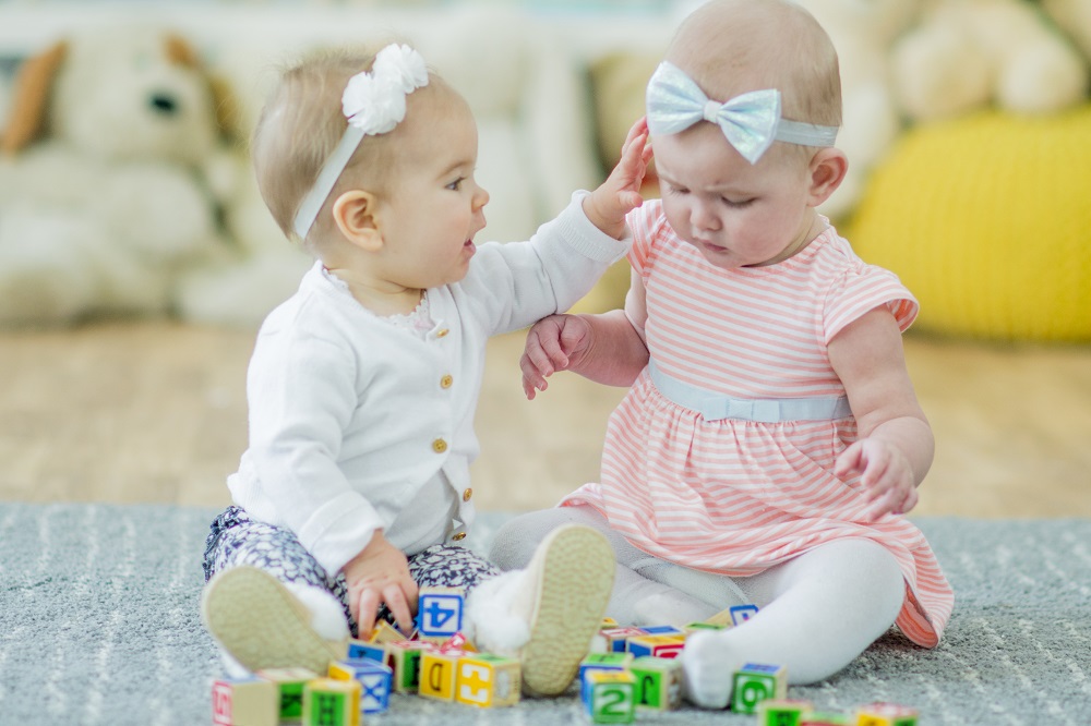 Twin babies on a playmat