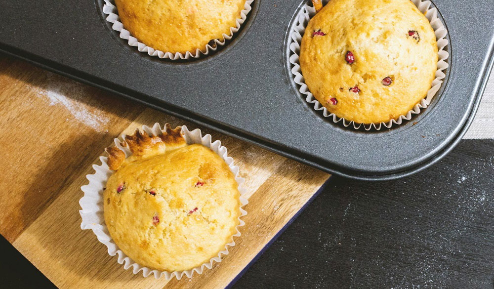 Healthy cranberry and orange muffins in a baking tray.