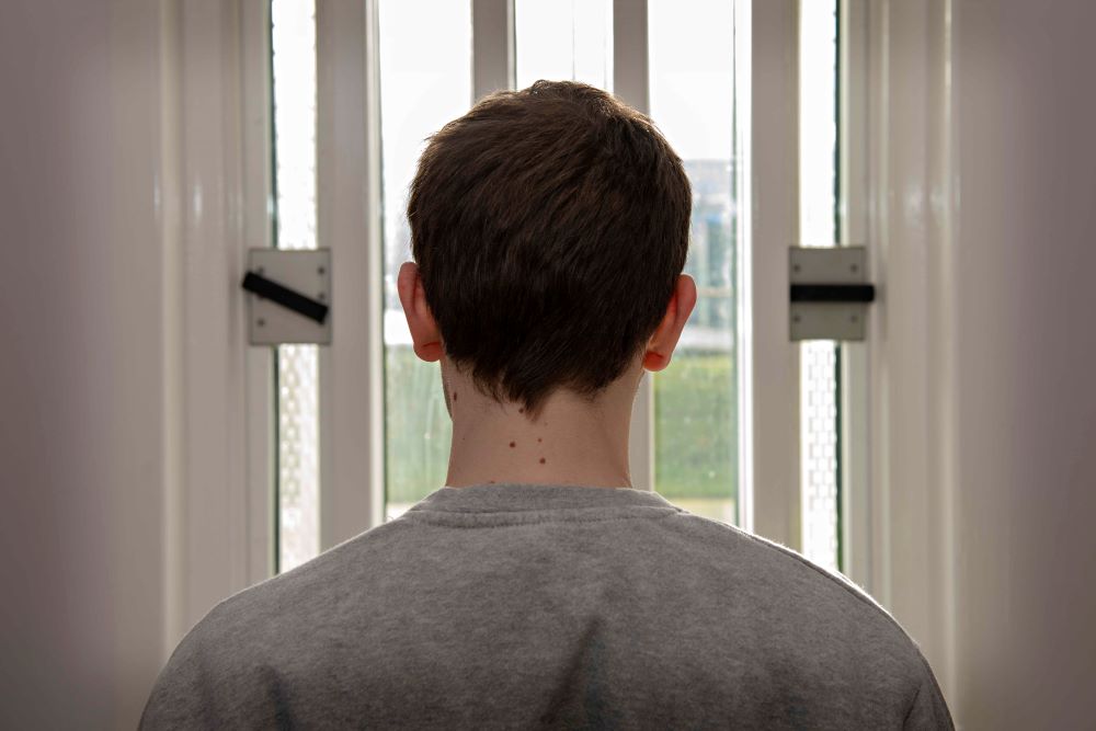 Teen boy looking out of a window.