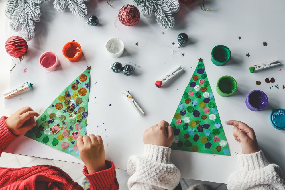 Children making Christmas trees out of paper, paint and buttons.