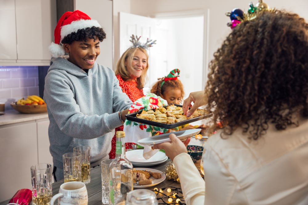 Teen boy offering his family festive food.