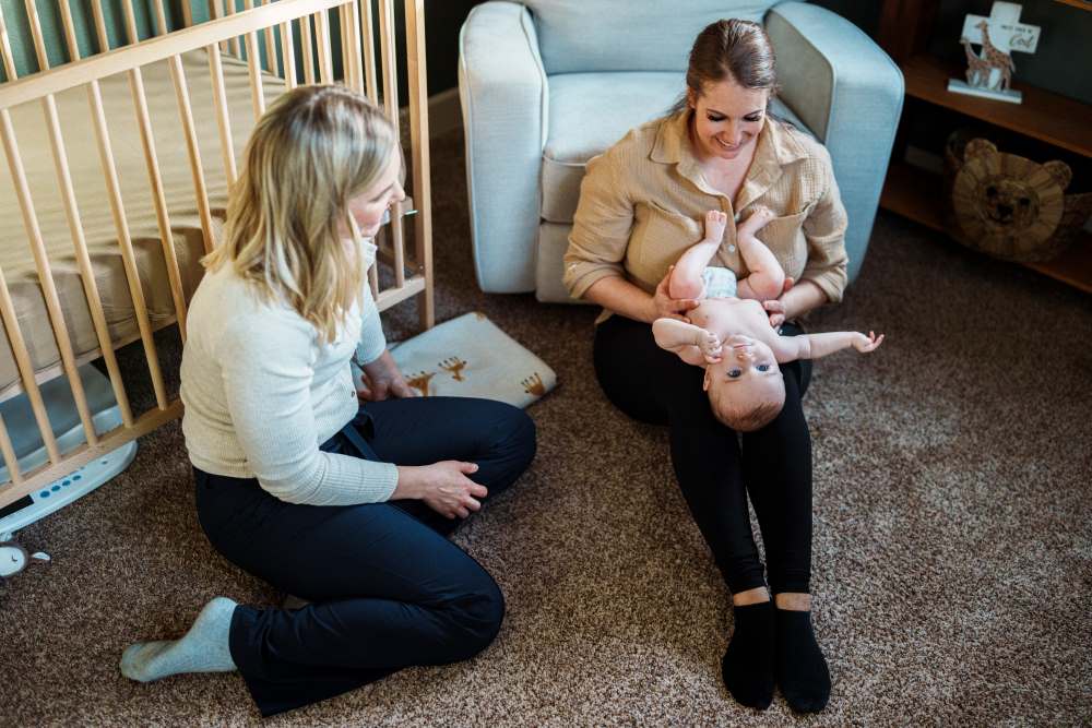 Mother holding her baby, talking to a friend.
