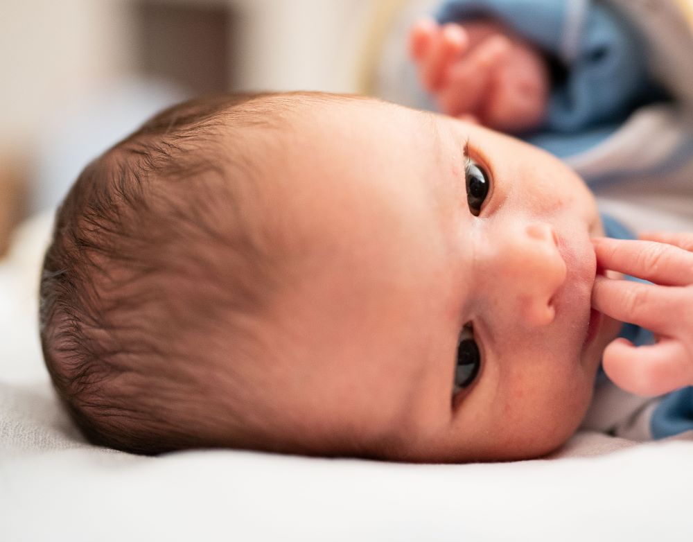 Baby holding their hand to their mouth.