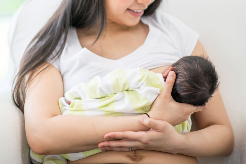 Mum holding her baby, smiling, while breastfeeding.