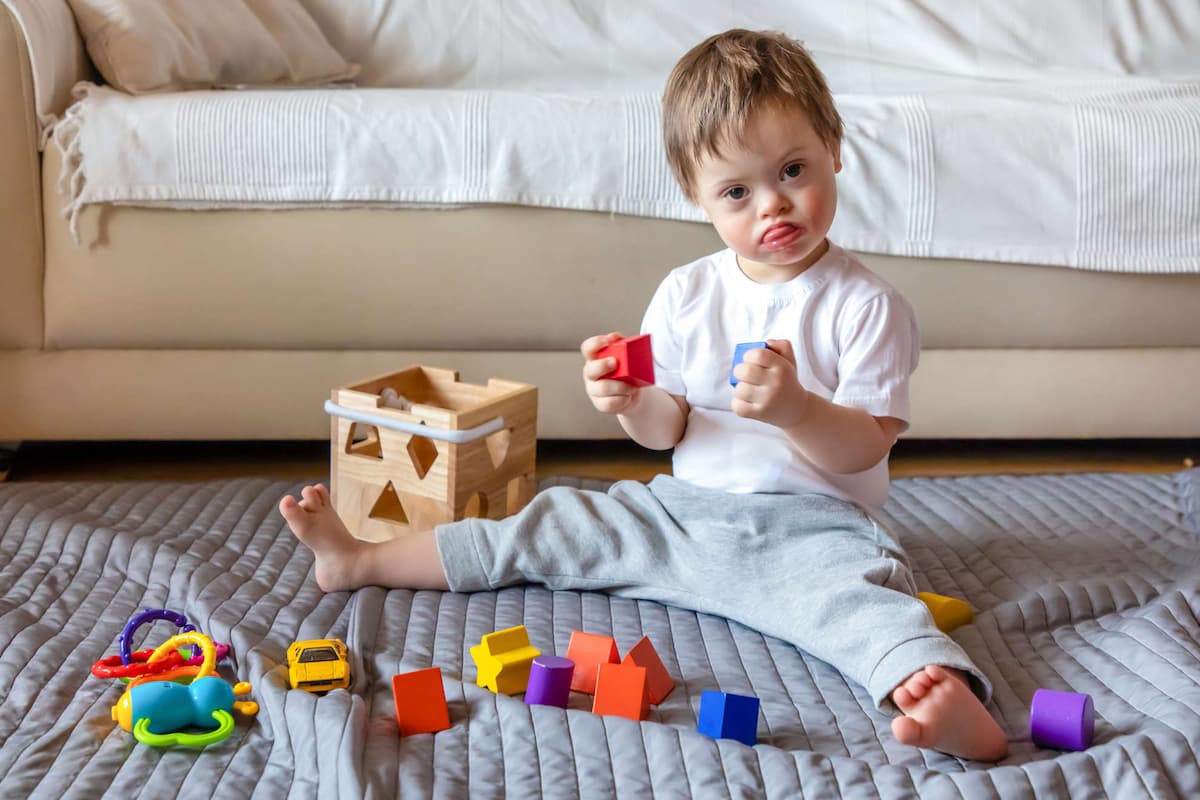 Photo of a baby boy sitting up and playing with blocks