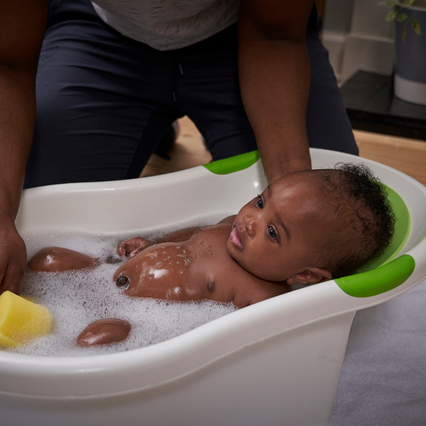 Image of an adult supporting a baby in a bath.