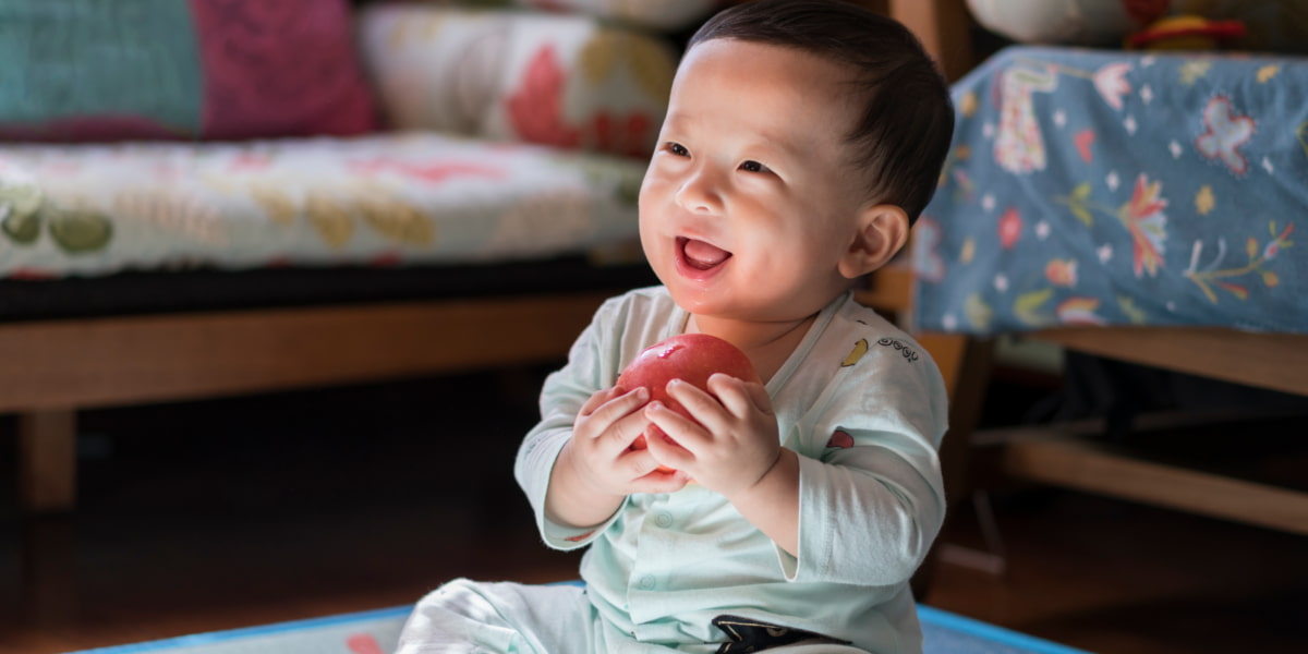 Photo of a baby sitting up and holding a toy