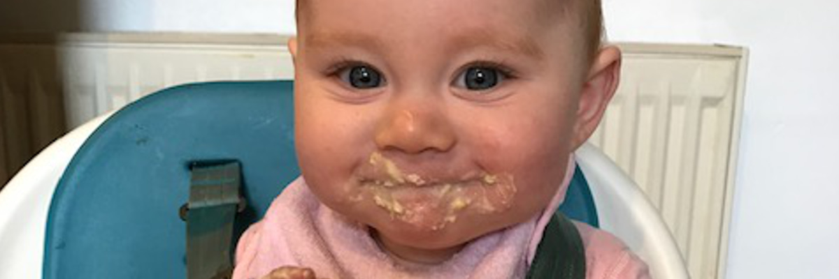 baby in highchair with yogurt on their face