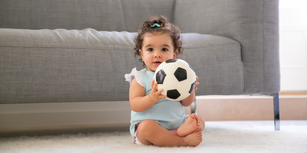 Photo of a baby with a ball in living room 