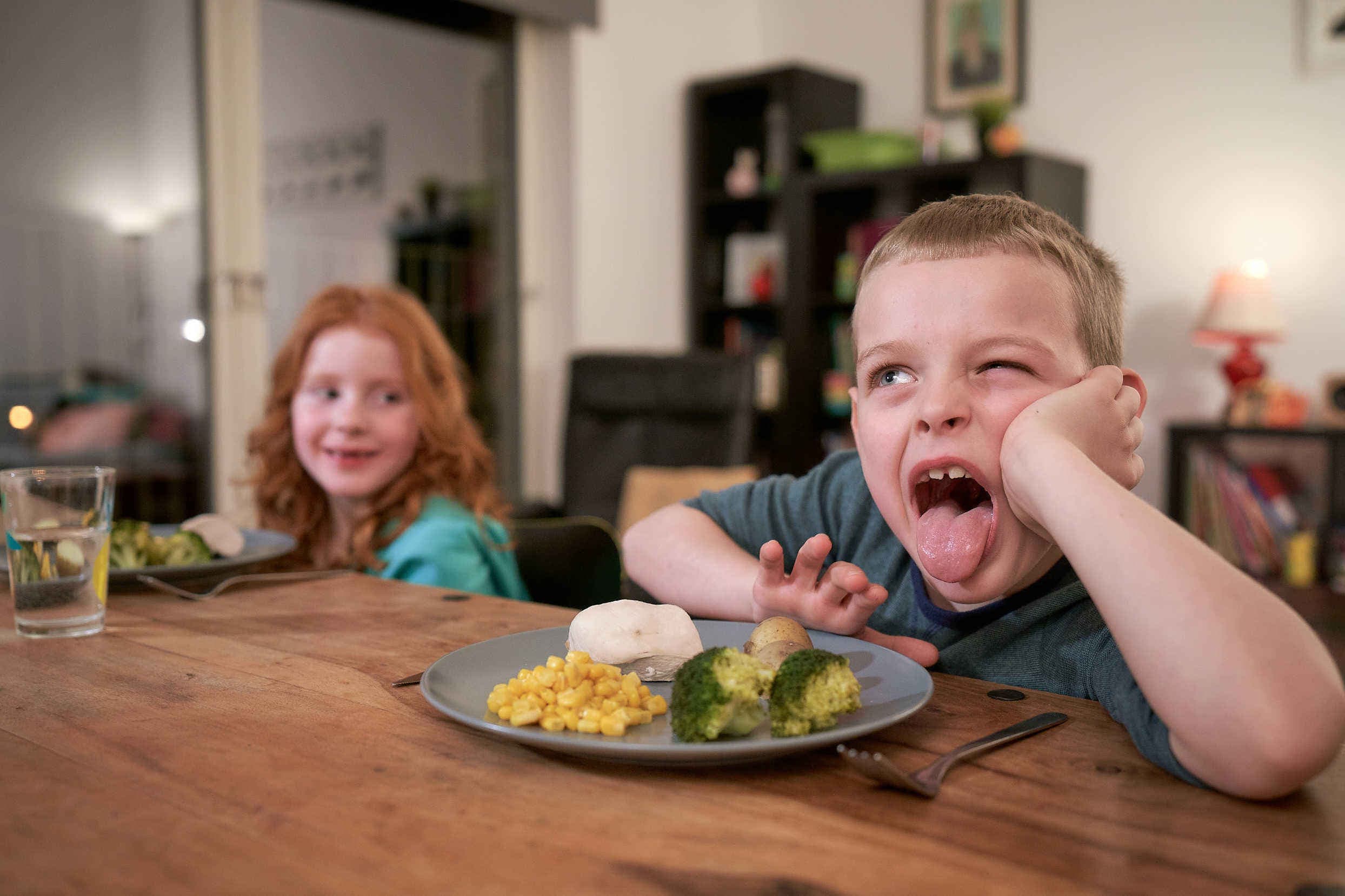 child pushing a plate of broccoli away from them