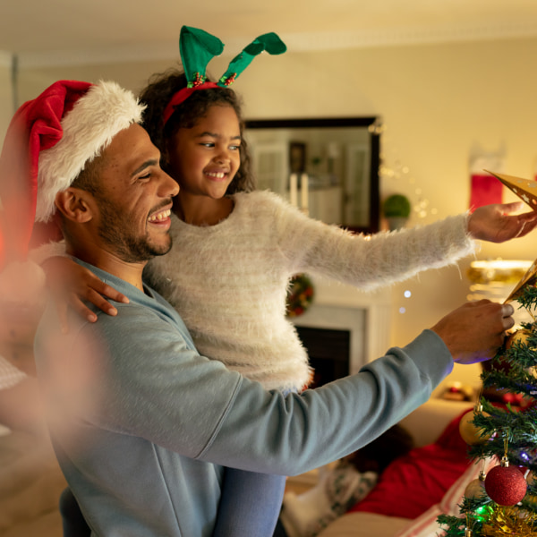 Photo of child and dad putting up Christmas decorations 