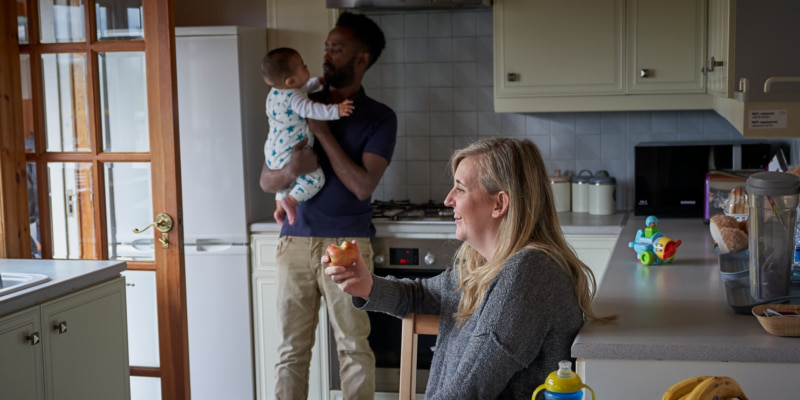 Photo of a couple smiling with their baby in the kitchen