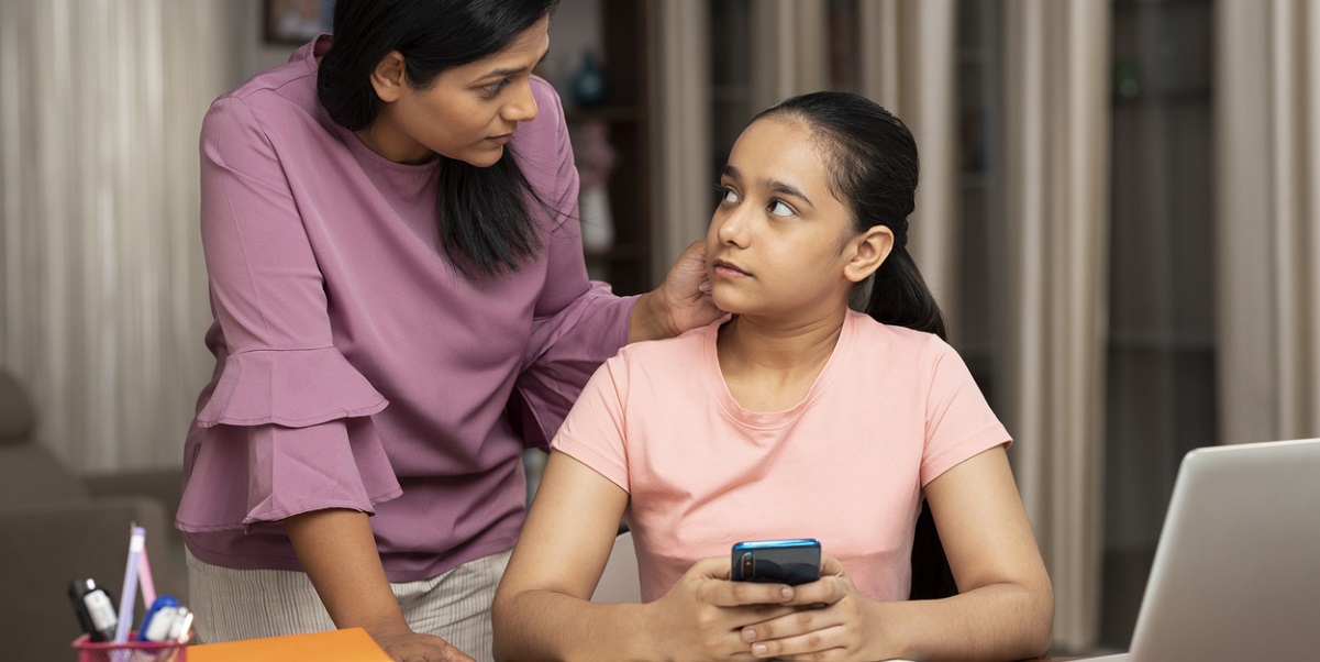 Mother and daughter talking. Daughter is holding a mobile phone.