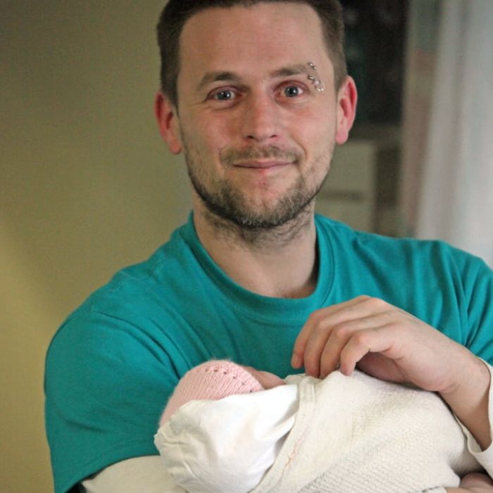 Smiling dad holding his baby wrapped in a blanket