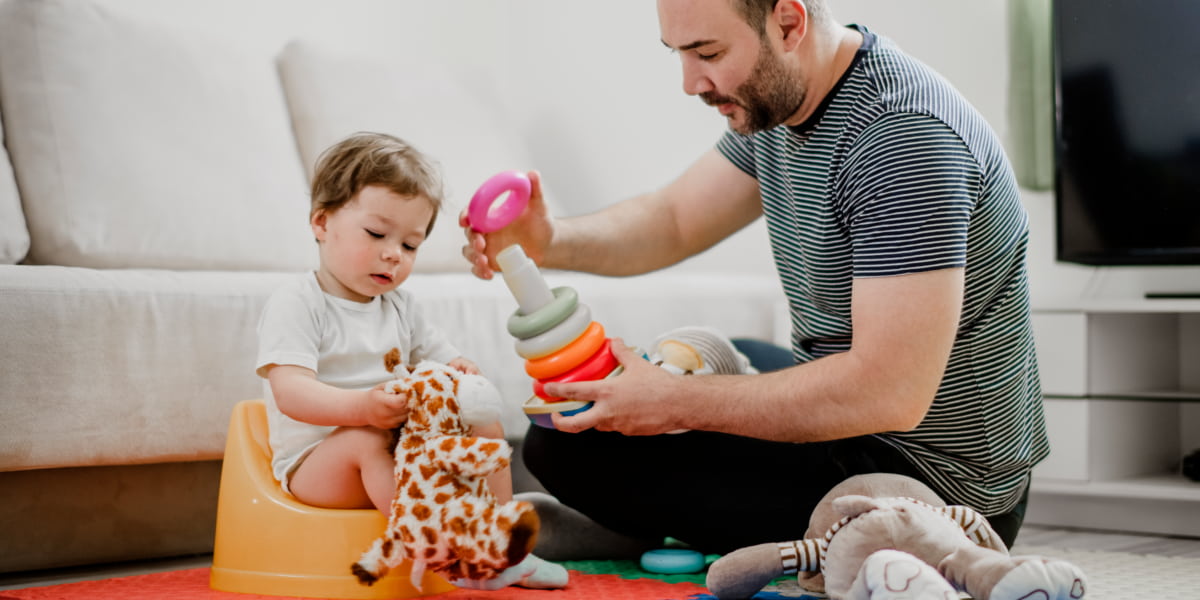 Image of a dad and toddler sitting next to each other and playing with toys.