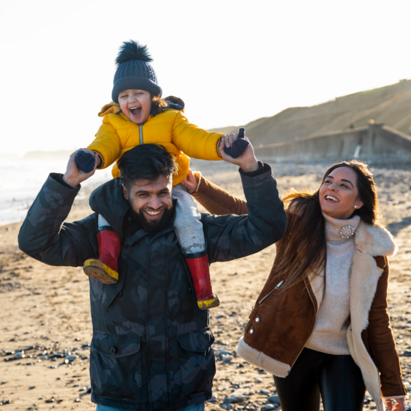 Family with toddler on a beach in winter, laughing together