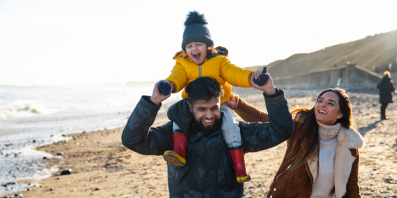 Family with toddler on a beach in winter, laughing together