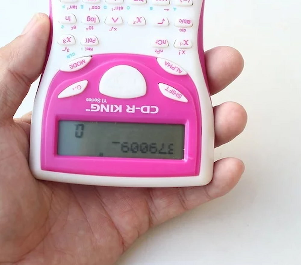 Image of a hand holding a pink calculator upside down.