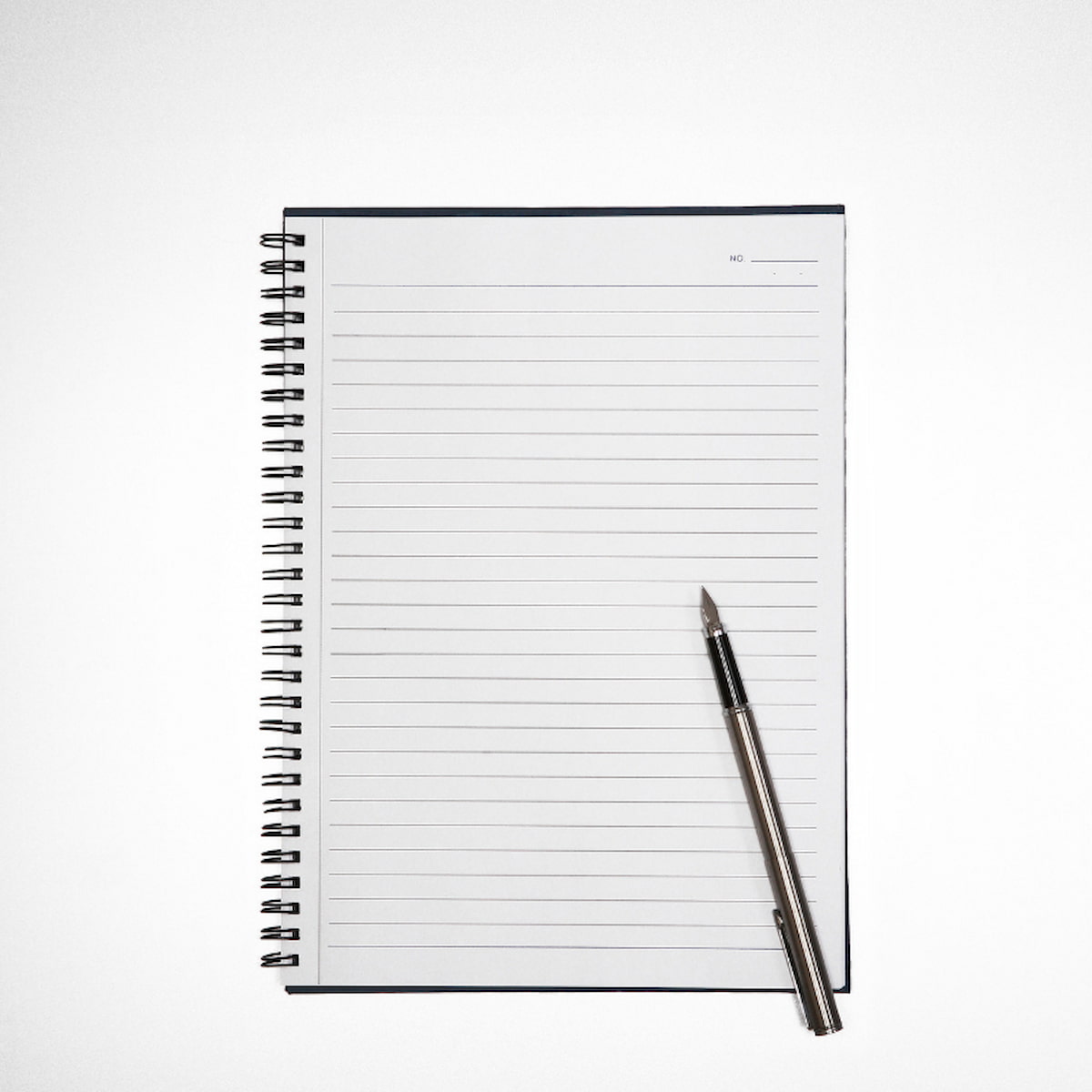 Image of a lined notebook with a pen sitting on top.