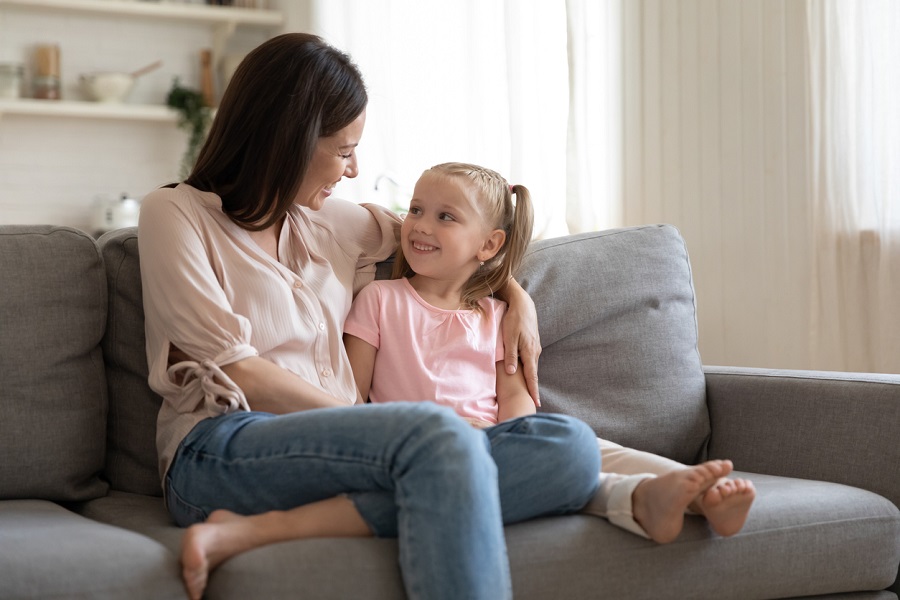Mother and young girl sitting on the sofa talking