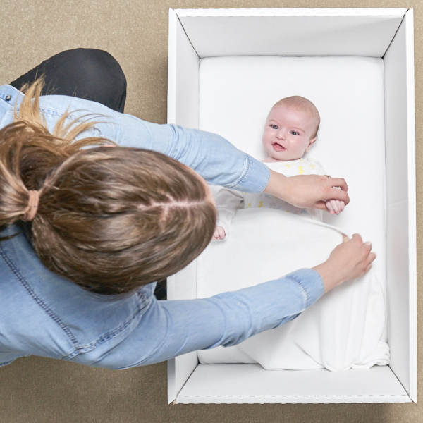 Photo of mum putting a baby to sleep in the baby box 