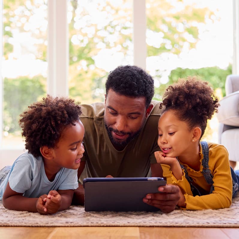 Dad and young girl and boy looking at a tablet together