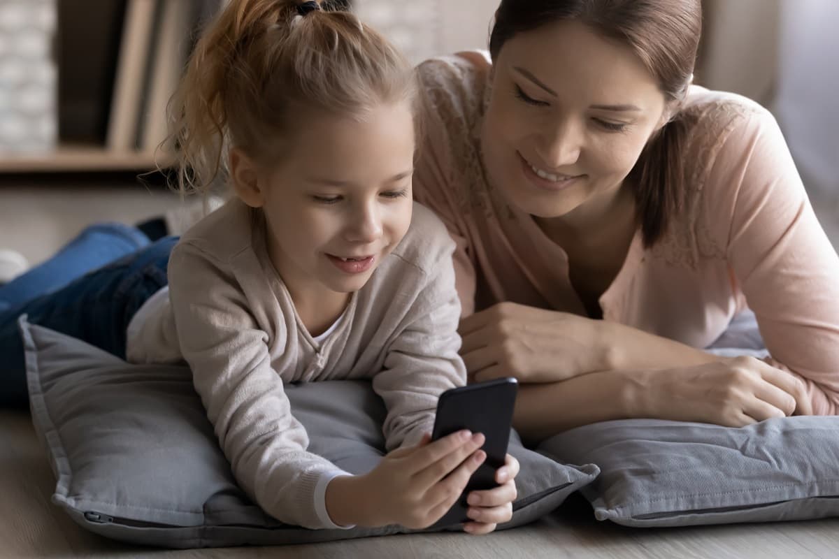 Smiling mum and young girl looking at a mobile phone