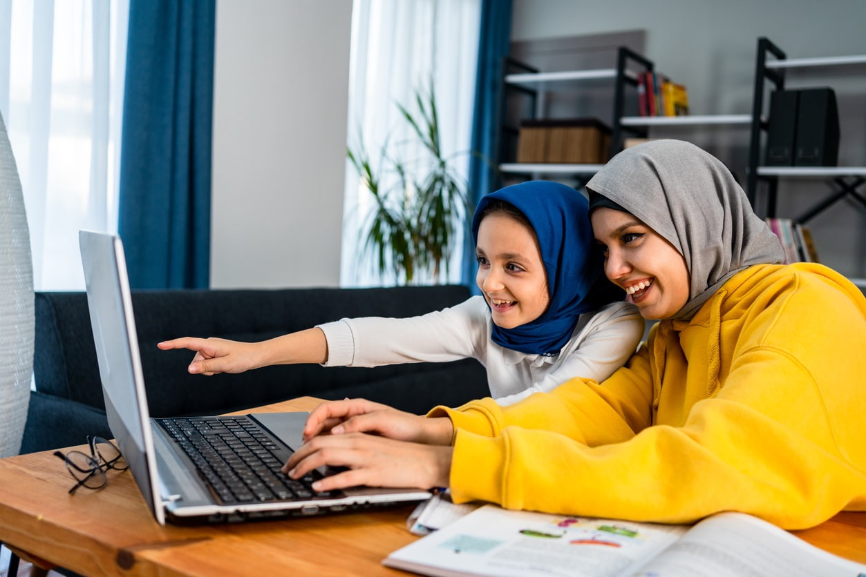 Muslim mum and daughter looking at a laptop together, smiling