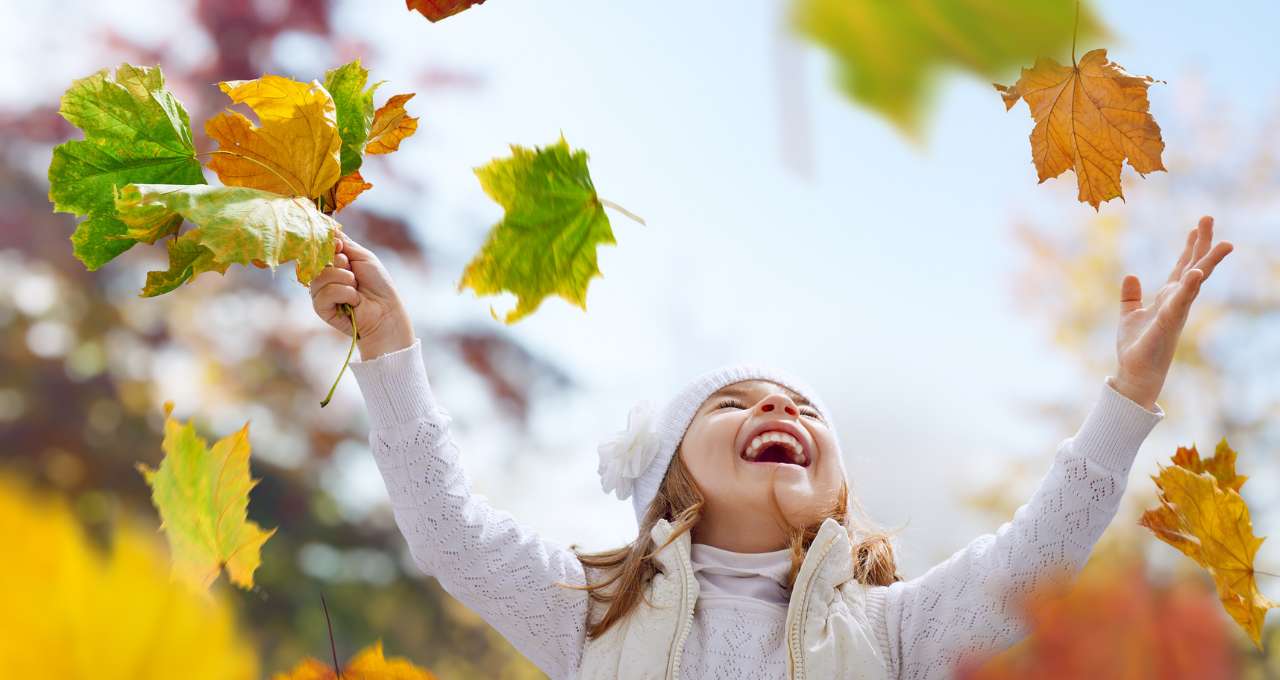 Child throwing autumn leaves into the air