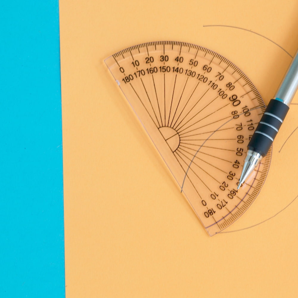 Image of a protractor on paper next to a pen.